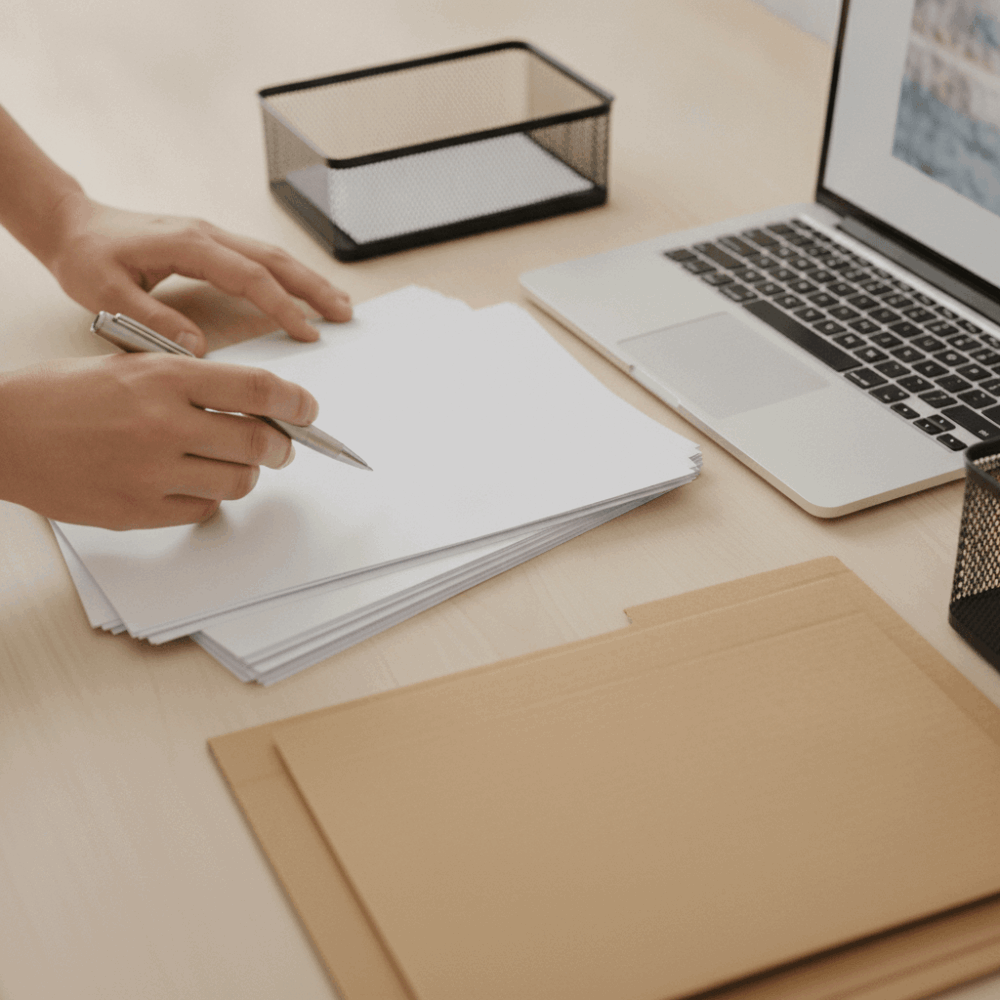 Mains triant et validant des documents de commandes B2B sur un bureau avec ordinateur portable ouvert